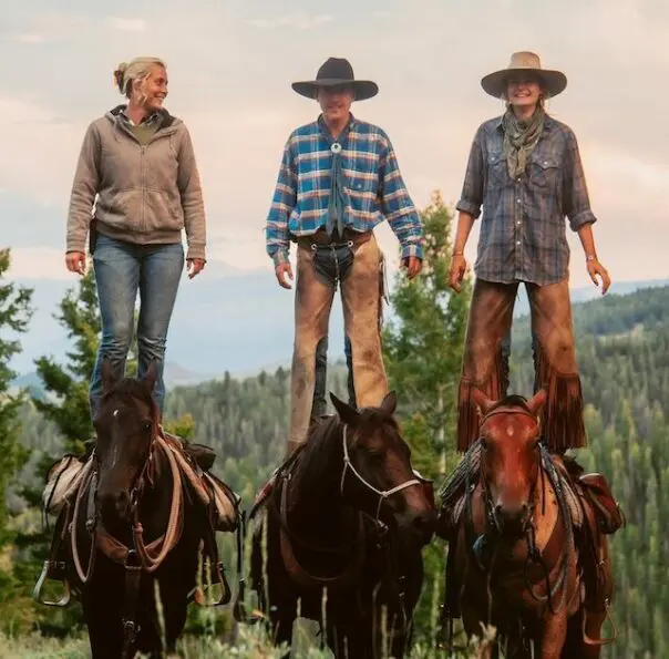 Three people standing on horseback in a scenic landscape, embodying a connection to the land and animal welfare.