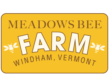 Yellow sign for "Meadows Bee Farm" in Windham, Vermont, with bee illustrations.