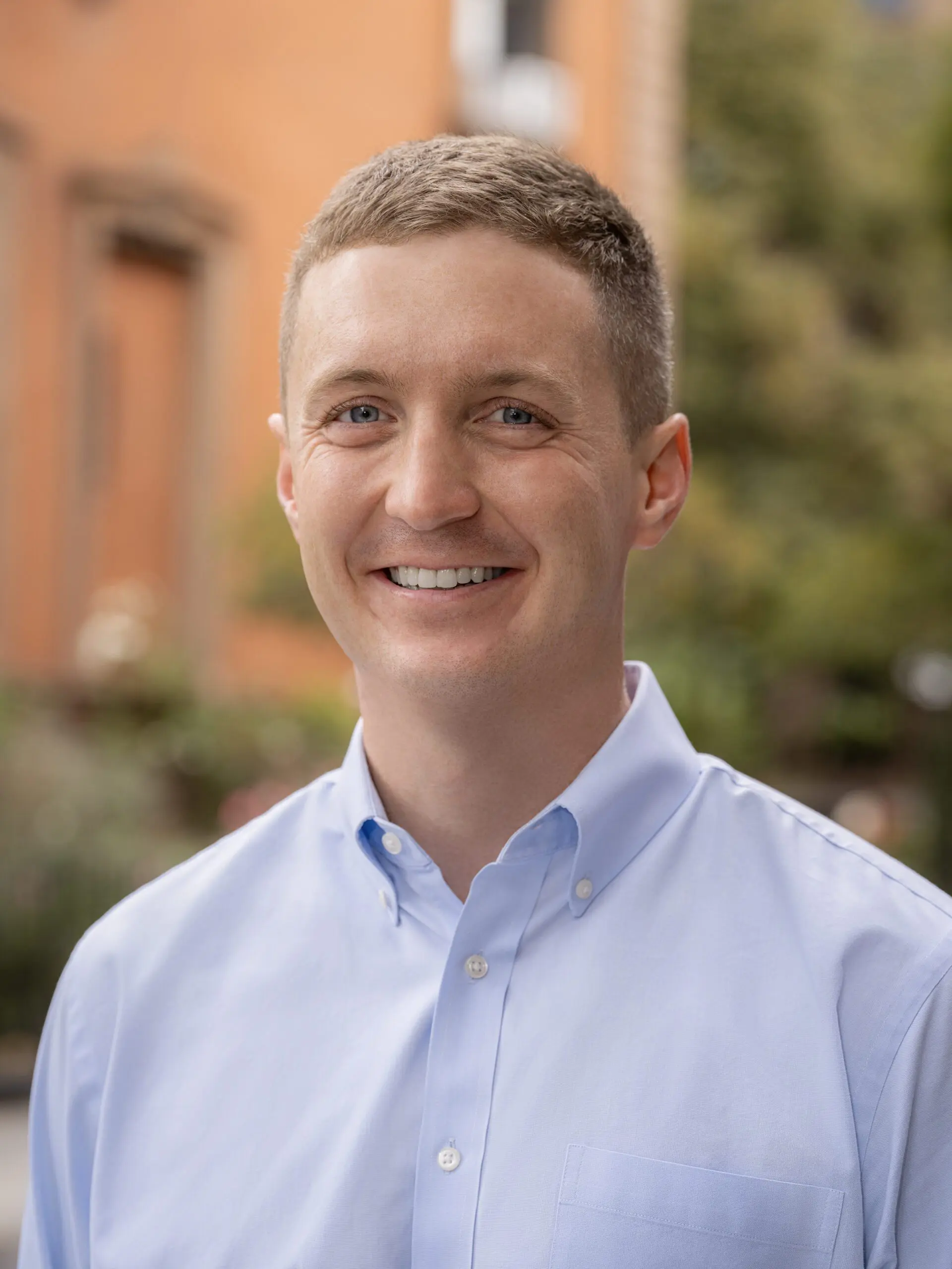 Food economist and author of Barons Austin Frerick smiles in a light blue button up shirt