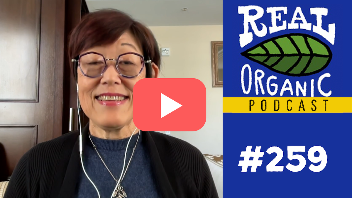 Nancy Maysumoto in her office, smiling with ear buds in
