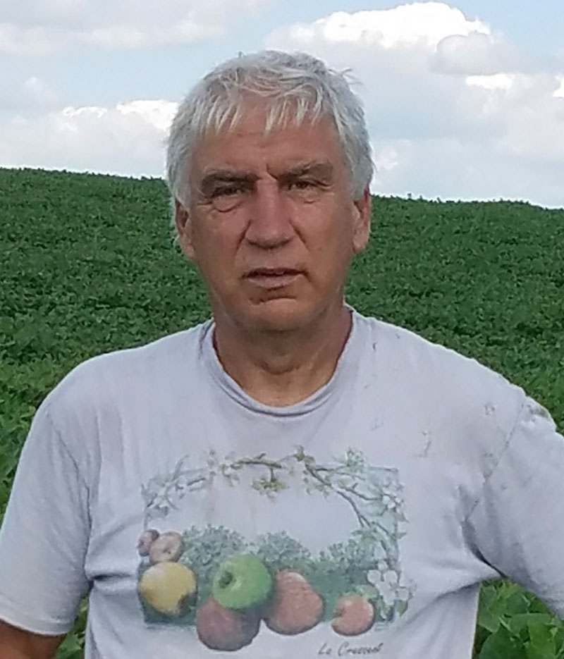 Francis Thicke in front of a lush green field wearing a t shirt with apples