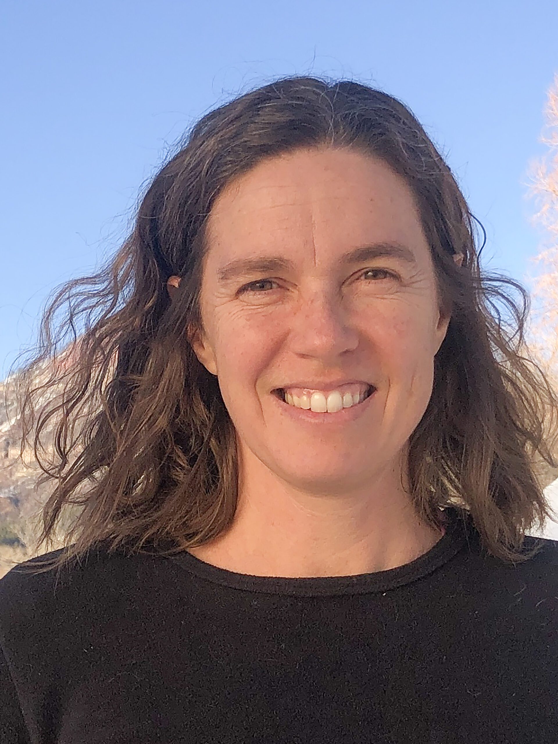 Farmer Linley Dixon smiles in a dark crewneck in front of a Colorado mountain